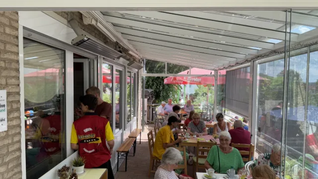 Volle Terrasse im Sommer, Gäste an den Tischen