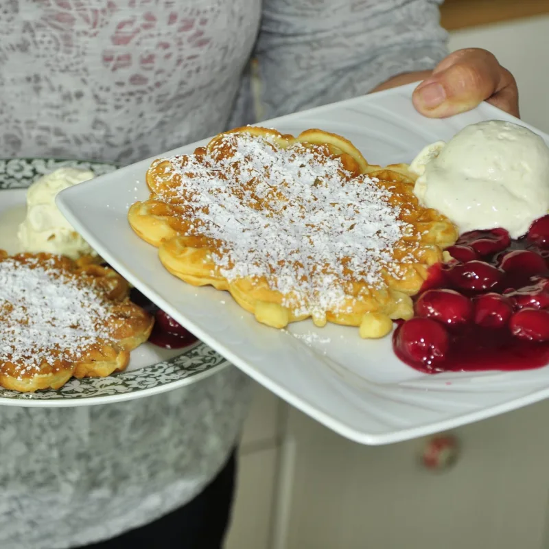 Zwei Waffelteller mit Kirschen und Sahne