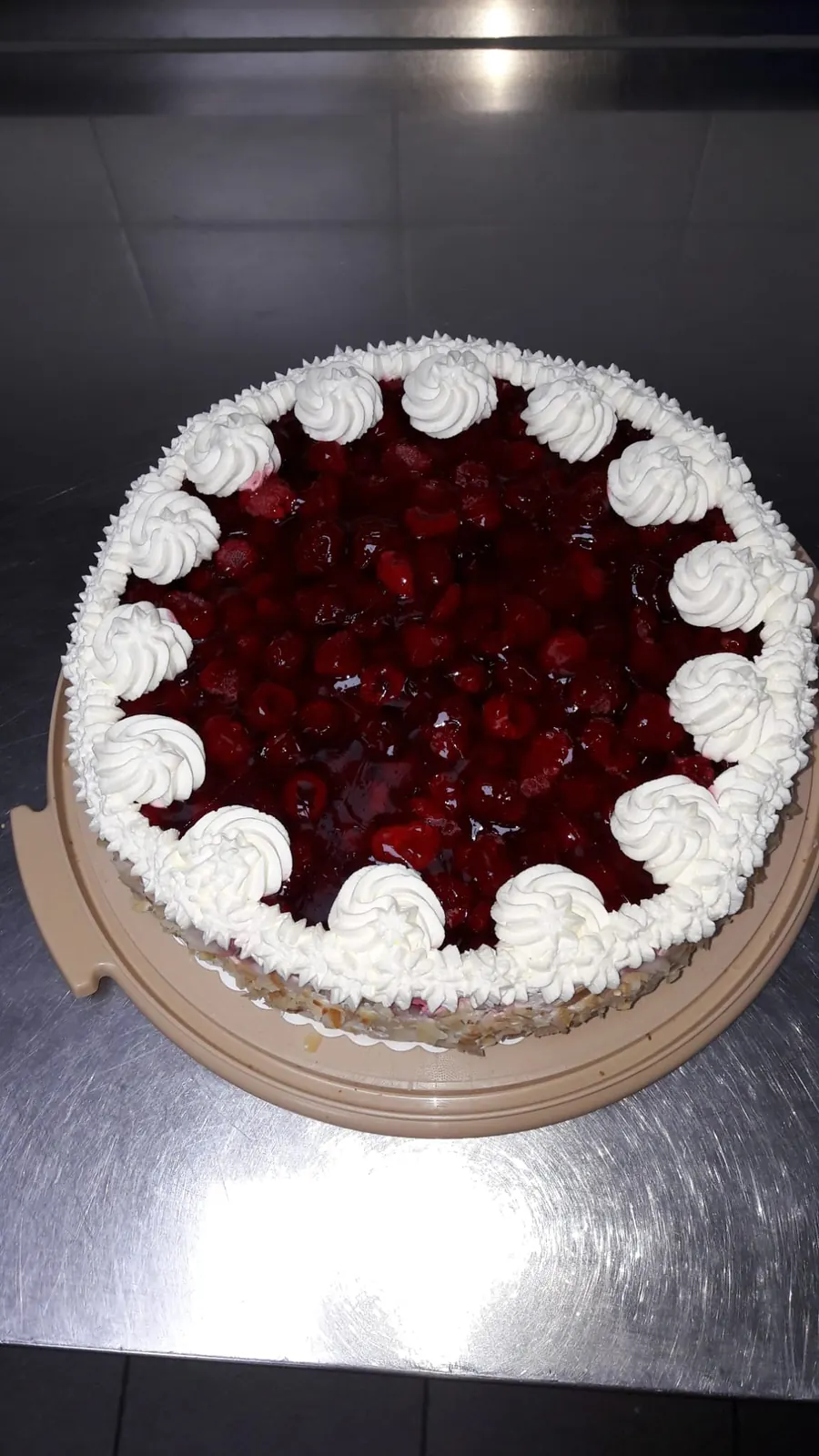 Hohe Sahnetorte mit Beerenbelag und Mandelrand