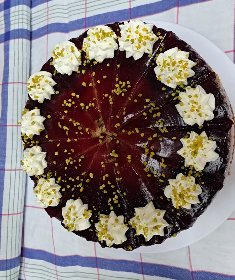 Torte mit dunkelroter Fruchtglasur und Pistazien